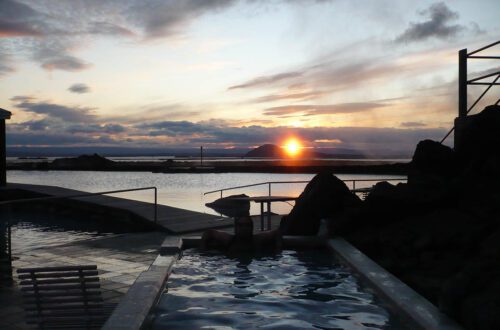 Lugares para bañarse en Islandia. Una terma islandesa con una puesta de sol al fondo.